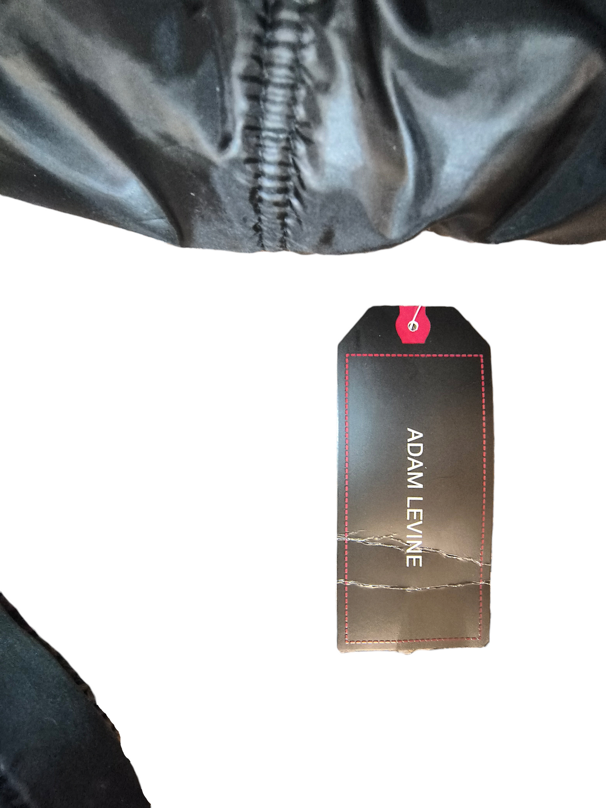 Awsum Thrift Adam Levine brand retail clothing tag with red stitching detail on a black background