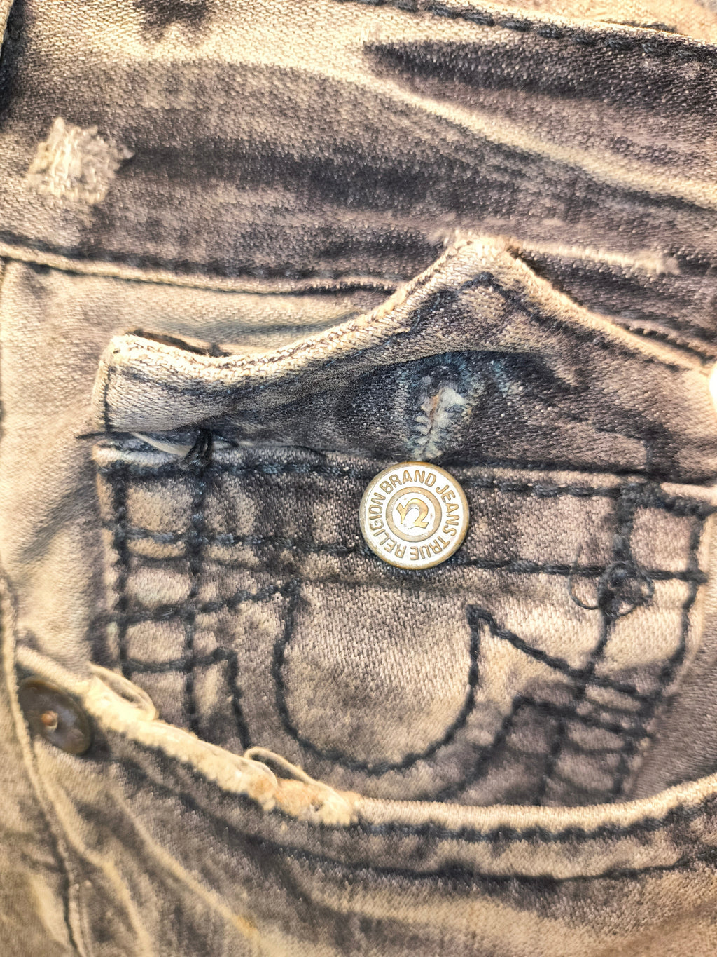 Awsum Thrift True Religion bell bottom jeans featuring a distressed grey wash and branded metal button detail