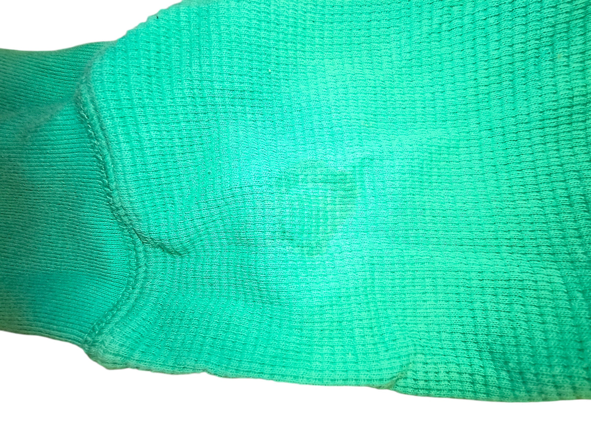 Close-up of a bright green textured fabric sleeve from an Awsum Thrift polo shirt showing ribbed cuff detail