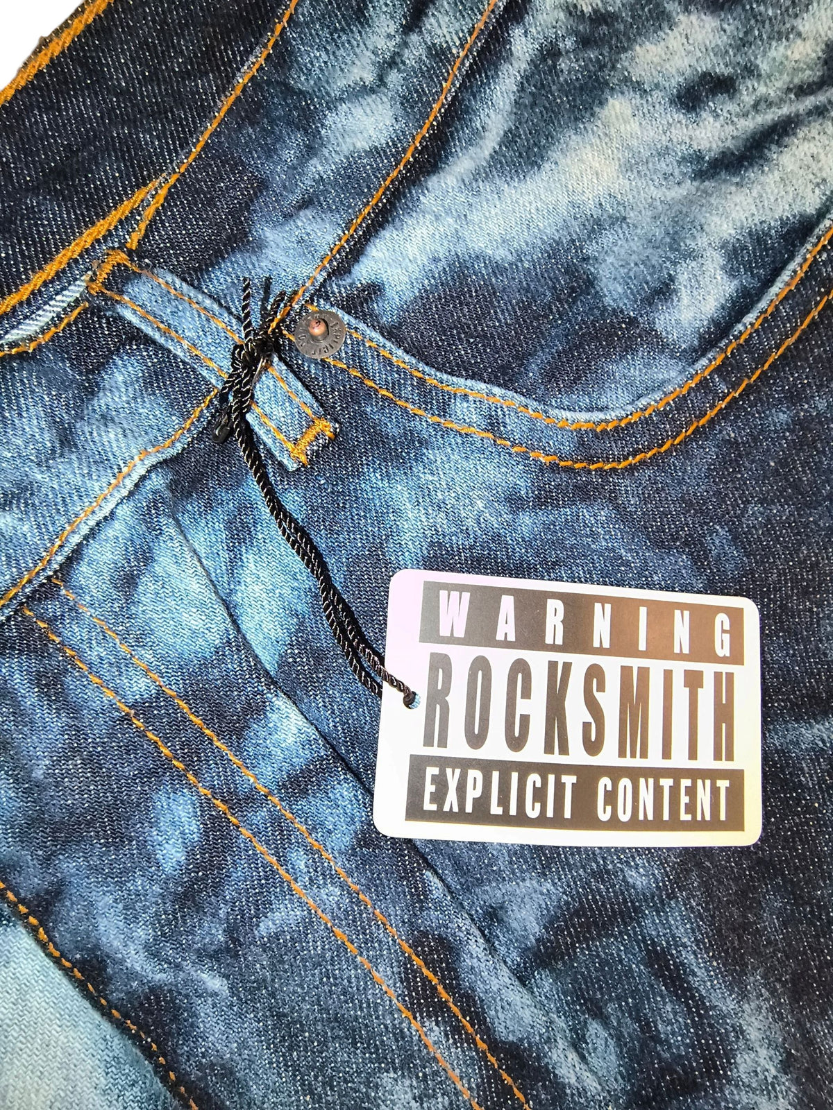 Awsum Thrift Rocksmith NYC branded hangtag with Warning Explicit Content text and black cord on a grey background.