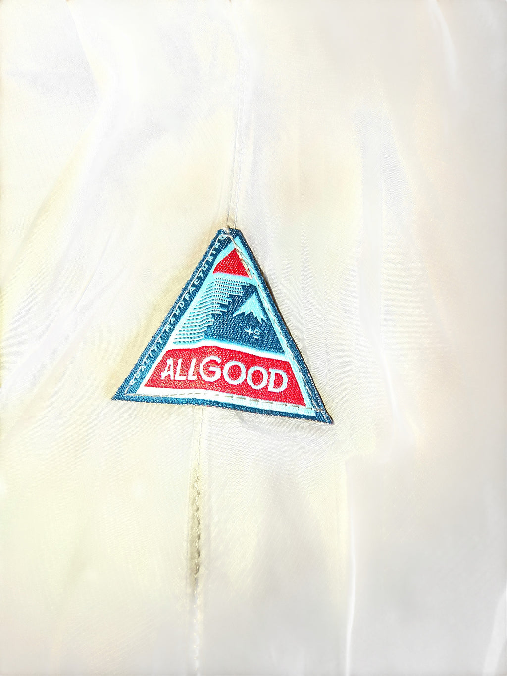 Awsum Thrift All Good triangular embroidered logo patch on a white technical waterproof fabric background