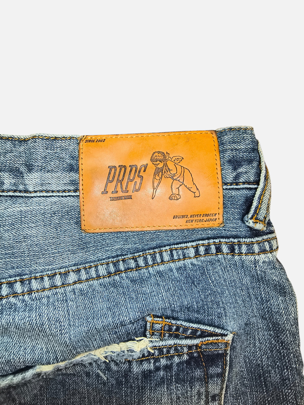 Awsum Thrift PRPS denim shorts featuring a tan leather brand patch with a cherub graphic and distressed detailing.