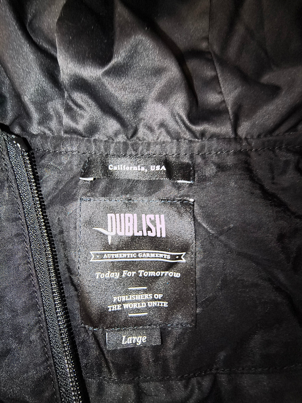Awsum Thrift Publish Brand interior clothing label on a matte black longline parka jacket in size large