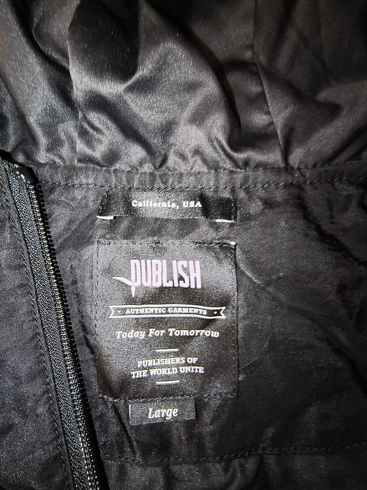 Awsum Thrift Publish Brand interior clothing label on a matte black longline parka jacket in size large