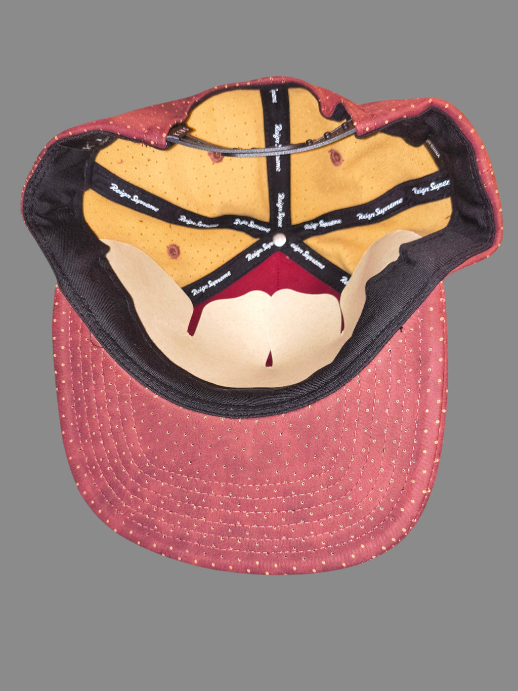 Interior view of Awsum Thrift King Apparel maroon perforated faux-leather snapback hat with branded seam taping.