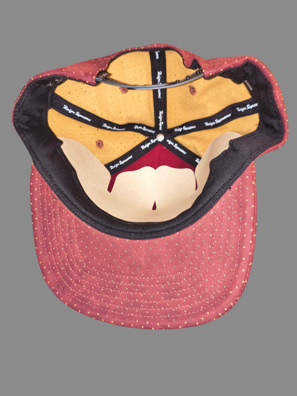 Interior view of Awsum Thrift King Apparel maroon perforated faux-leather snapback hat with branded seam taping.