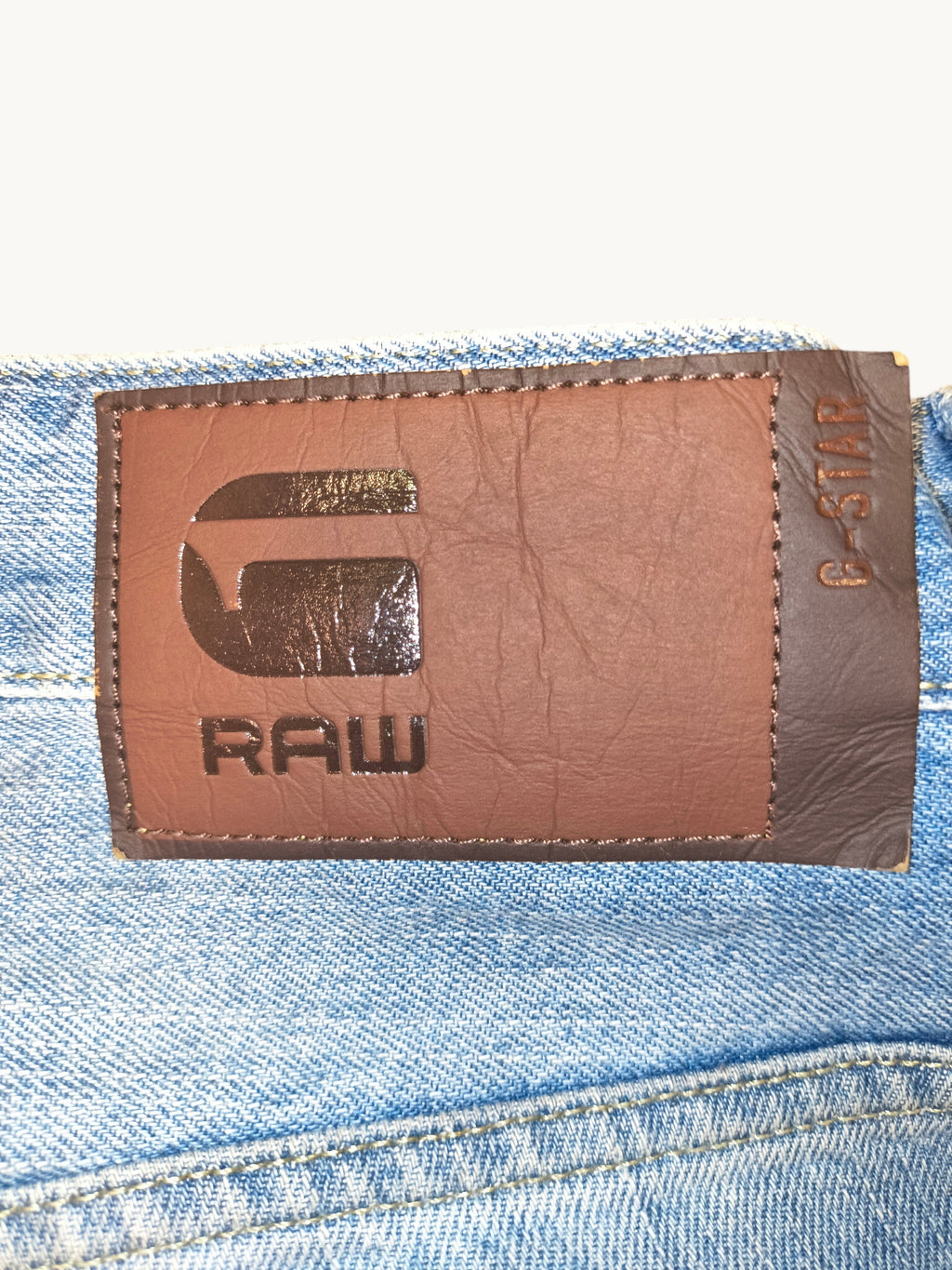 Awsum Thrift G-Raw jean shorts featuring a brown leather branded patch on light blue denim fabric