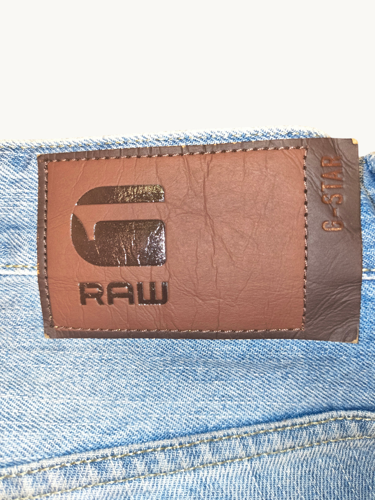 Awsum Thrift G-Raw jean shorts featuring a brown leather branded patch on light blue denim fabric