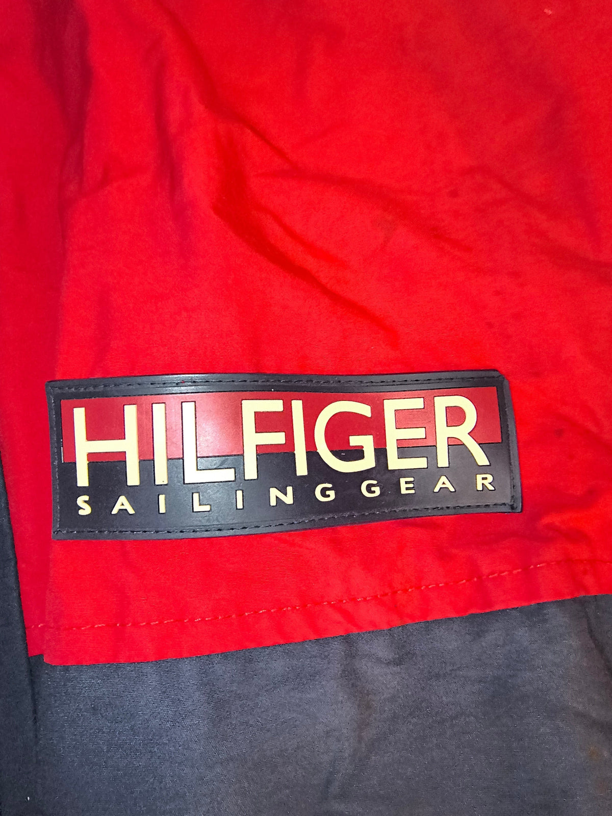 Awsum Thrift vintage Tommy Hilfiger Sailing Gear logo patch in red, navy, and yellow on a black background