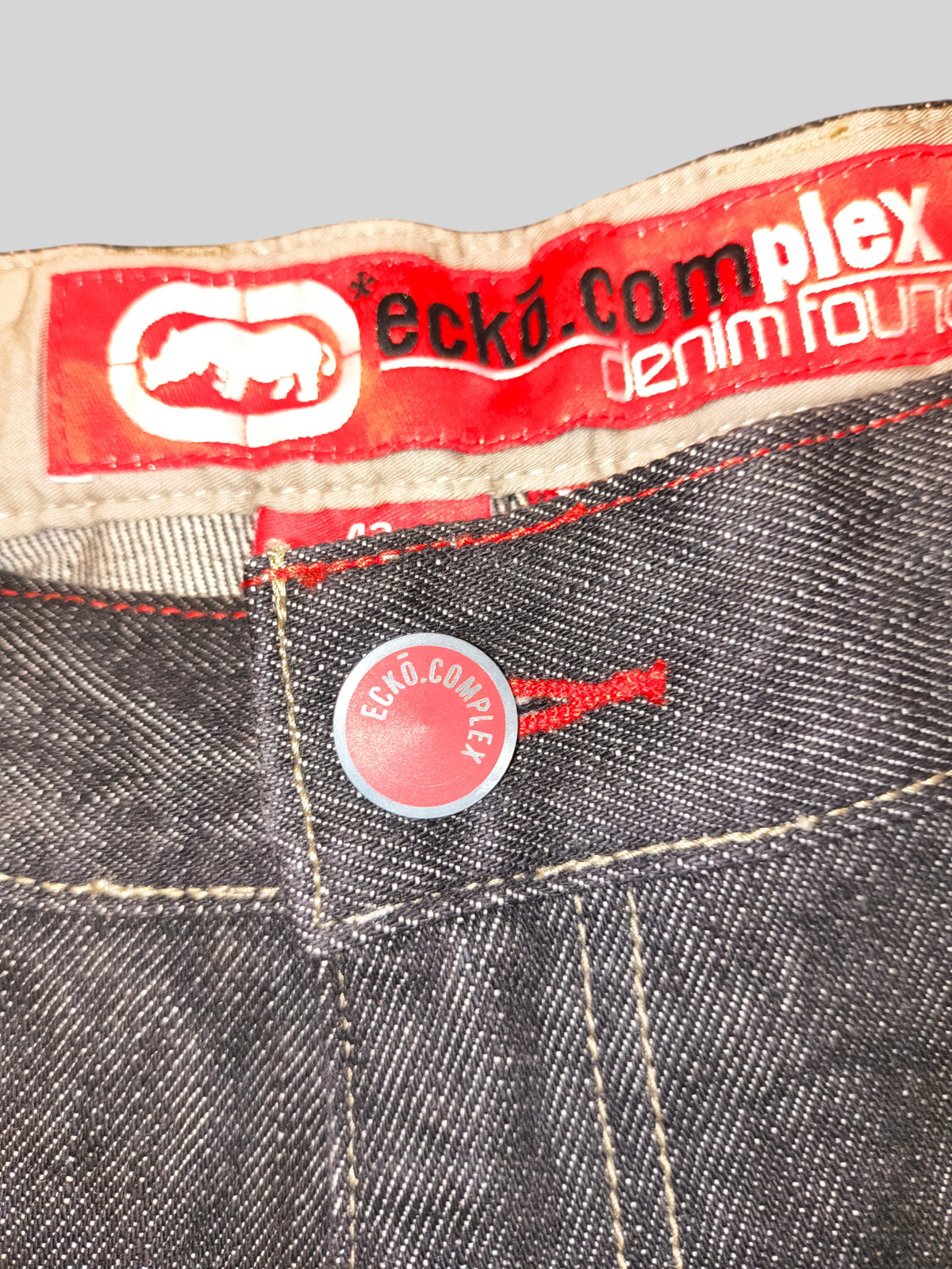 Awsum Thrift Ecko Unltd carpenter jeans featuring a red branded waist label and a matching red button closure.