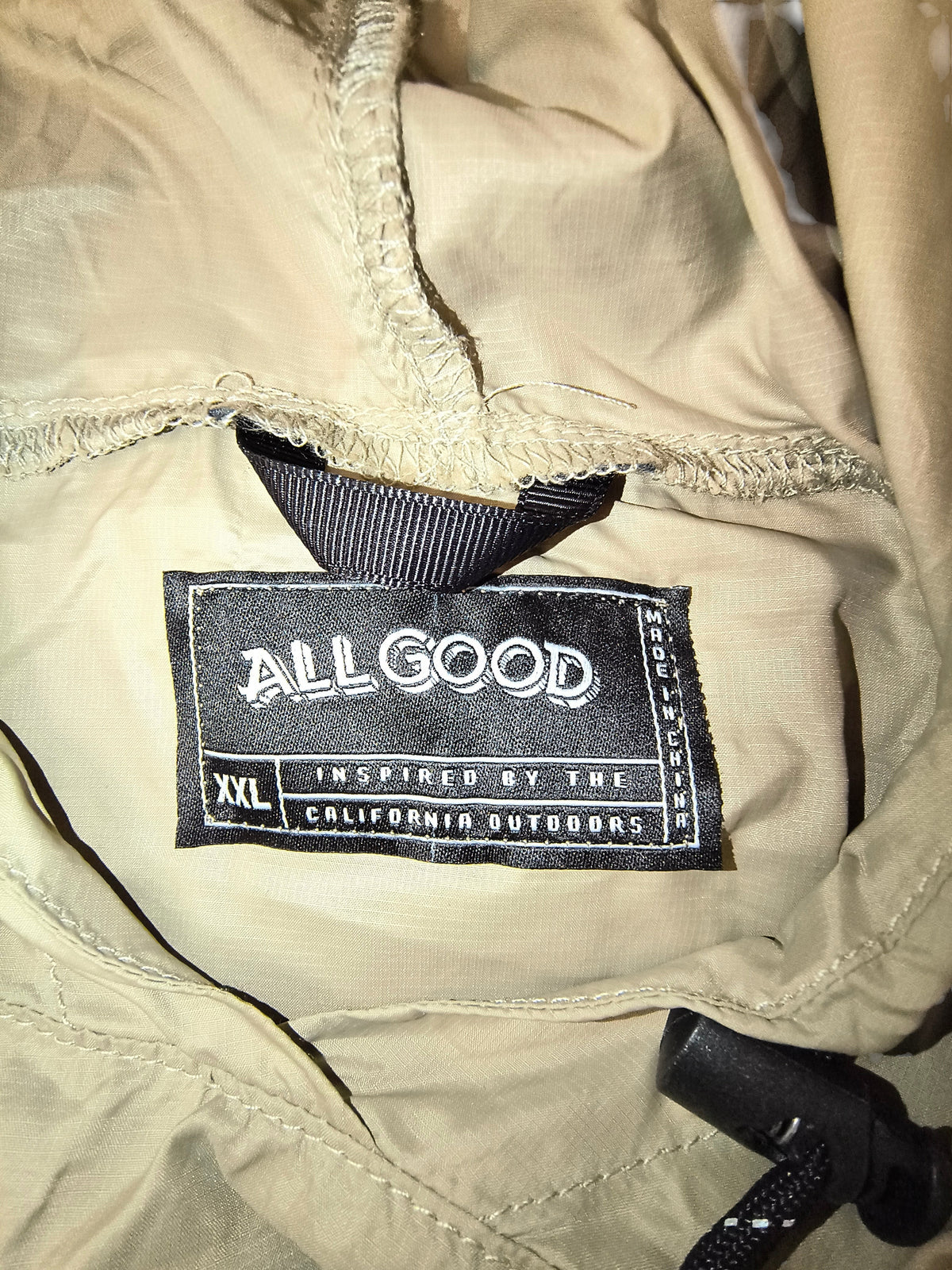 Awsum Thrift All Good brand label on a khaki tan waterproof technical rain poncho in size XXL