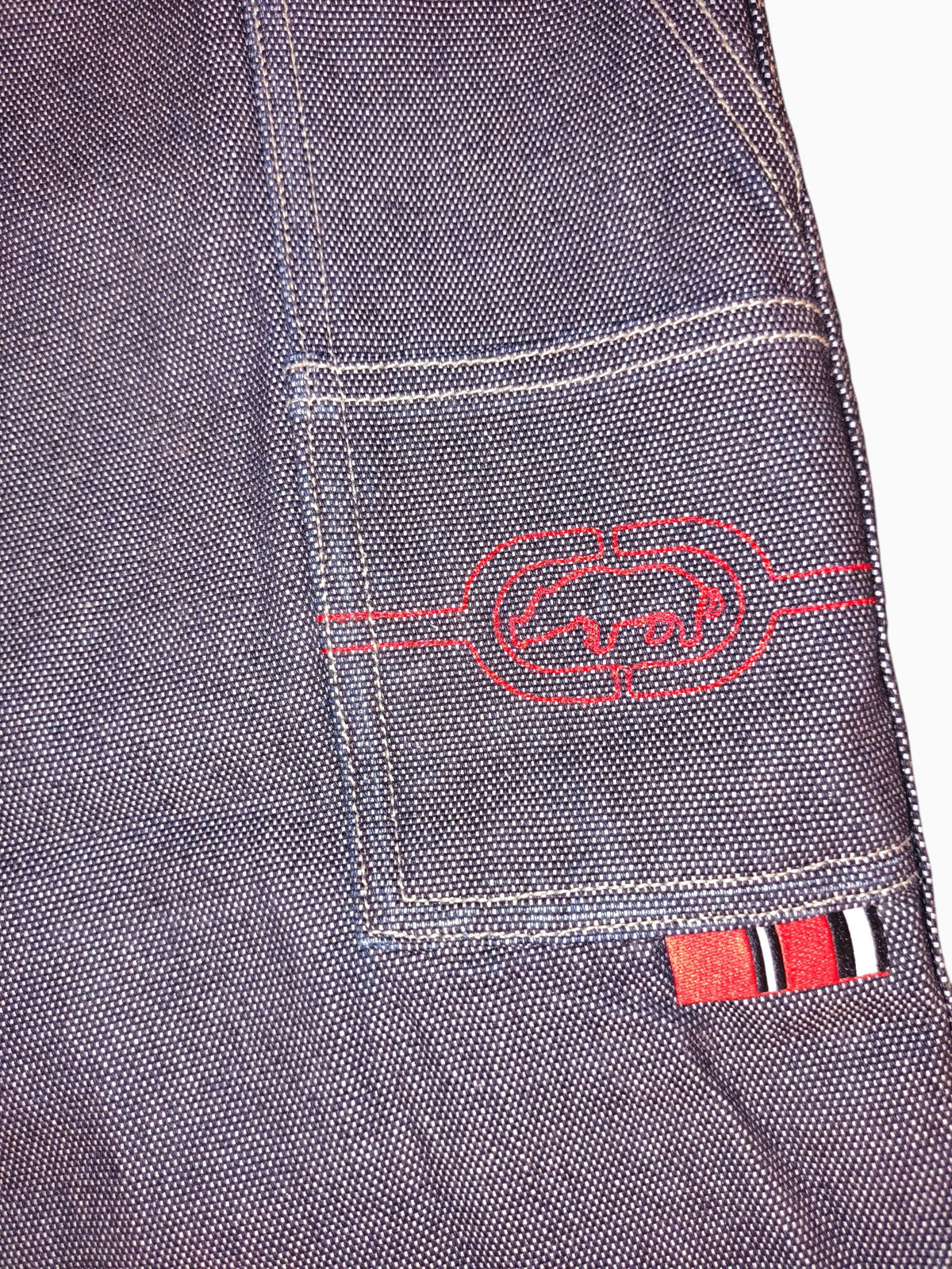Awsum Thrift vintage Marc Ecko dark indigo raw denim jeans with red embroidered rhino logo and tool pocket detail.
