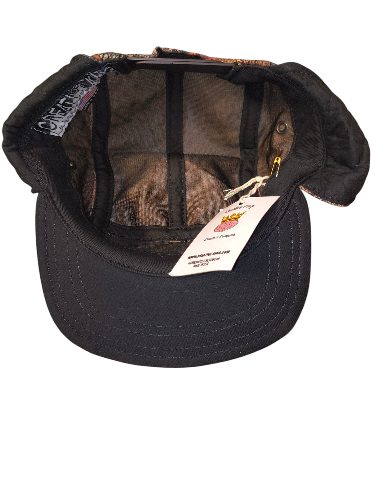 Awsum Thrift Creative King Hat Co. 5-panel camper hat with ear flaps, black brim, and camo tapestry interior lining.