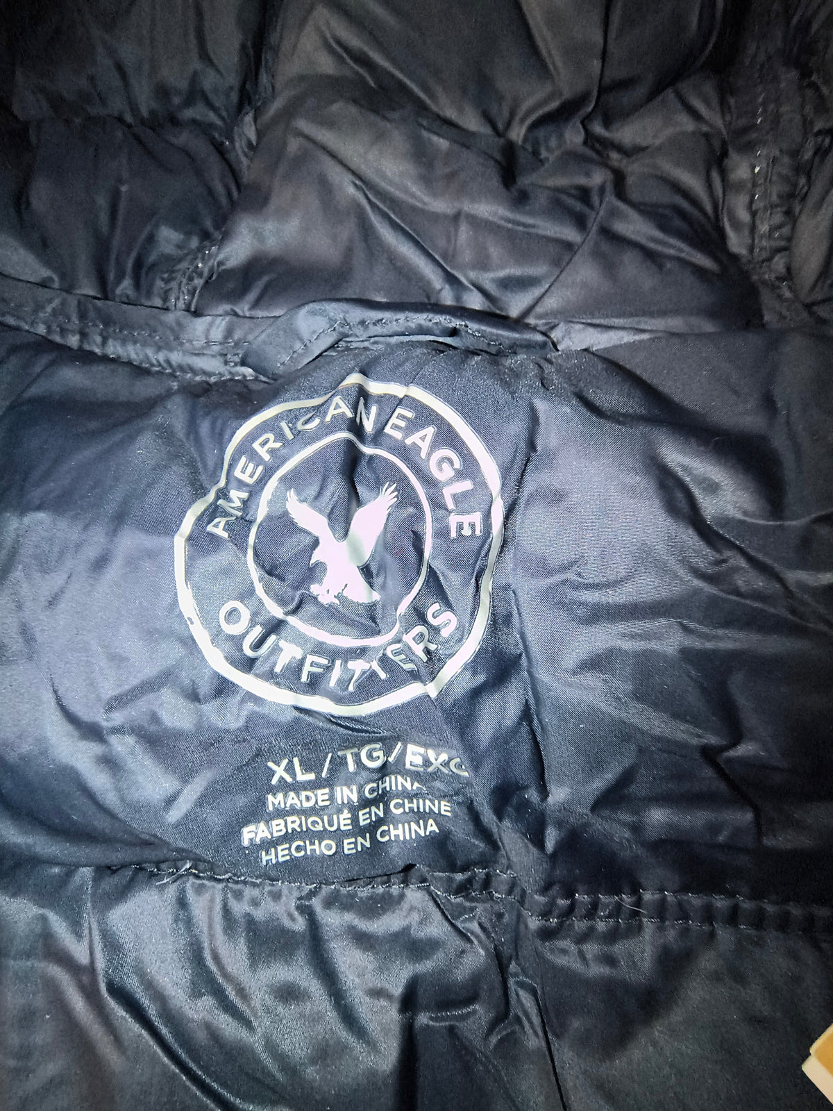 Awsum Thrift American Eagle metallic silver puffer jacket sleeve with circular logo patch and size label
