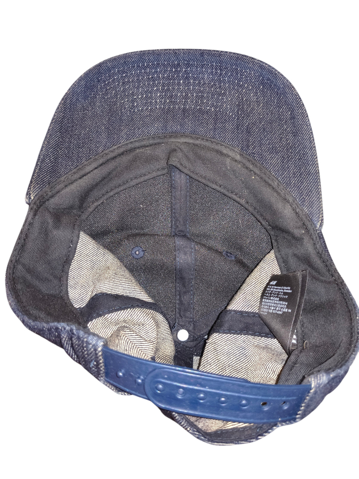 Awsum Thrift H&M blue denim snapback hat interior view showing adjustable plastic strap and brand care label