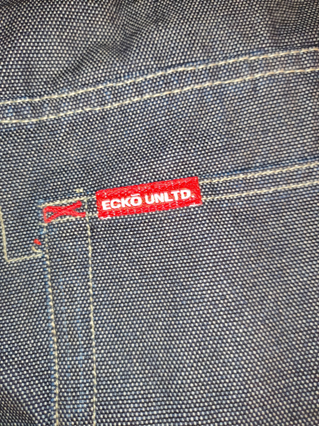 Awsum Thrift vintage Marc Ecko dark indigo raw denim jeans featuring a red Ecko Unltd logo tag and contrast stitching