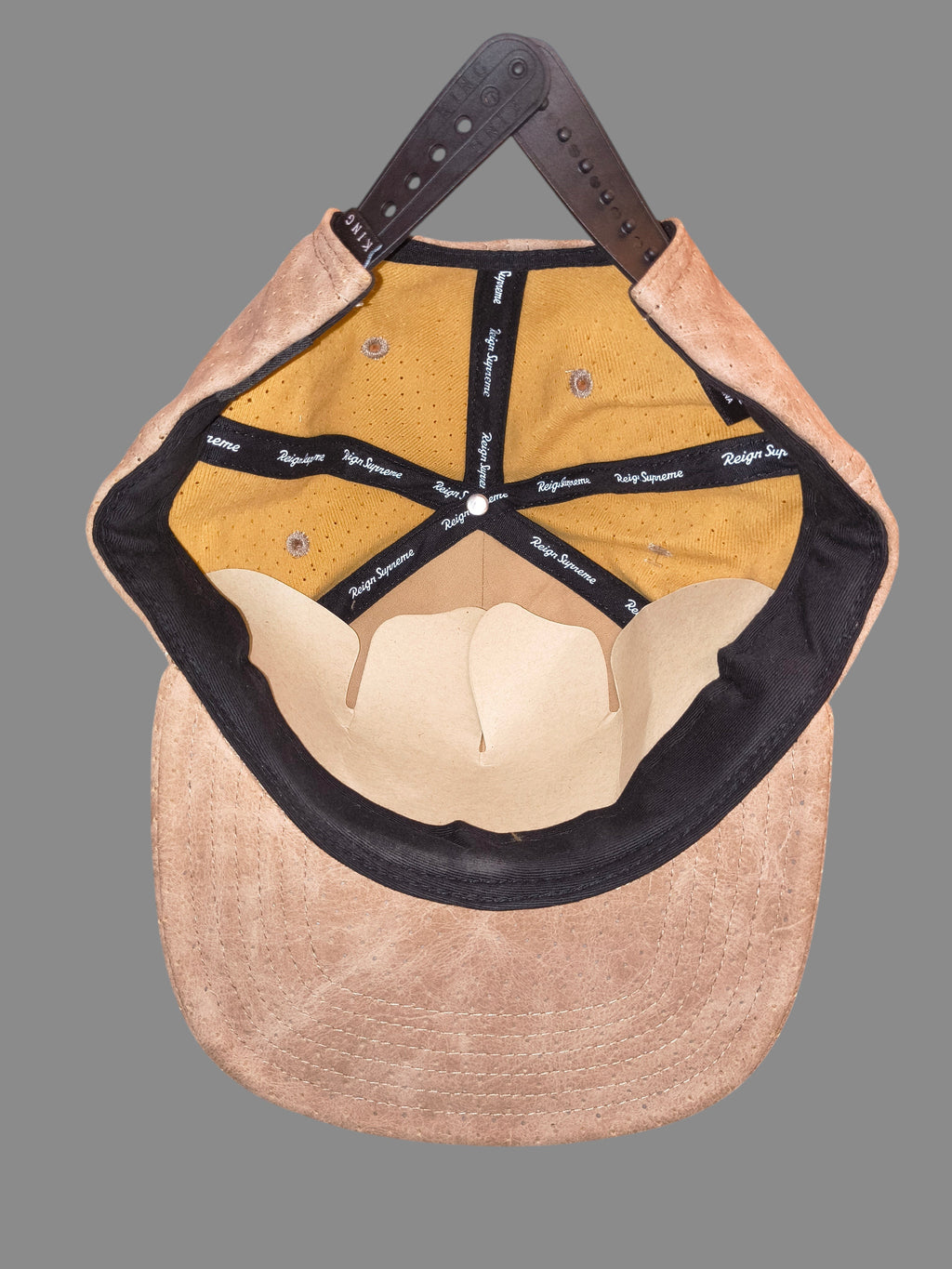 Awsum Thrift King Apparel tan perforated faux-leather snapback hat interior view with gold mesh lining and branding.