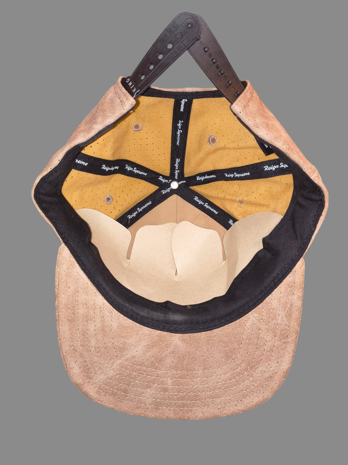 Awsum Thrift King Apparel tan perforated faux-leather snapback hat interior view with gold mesh lining and branding.