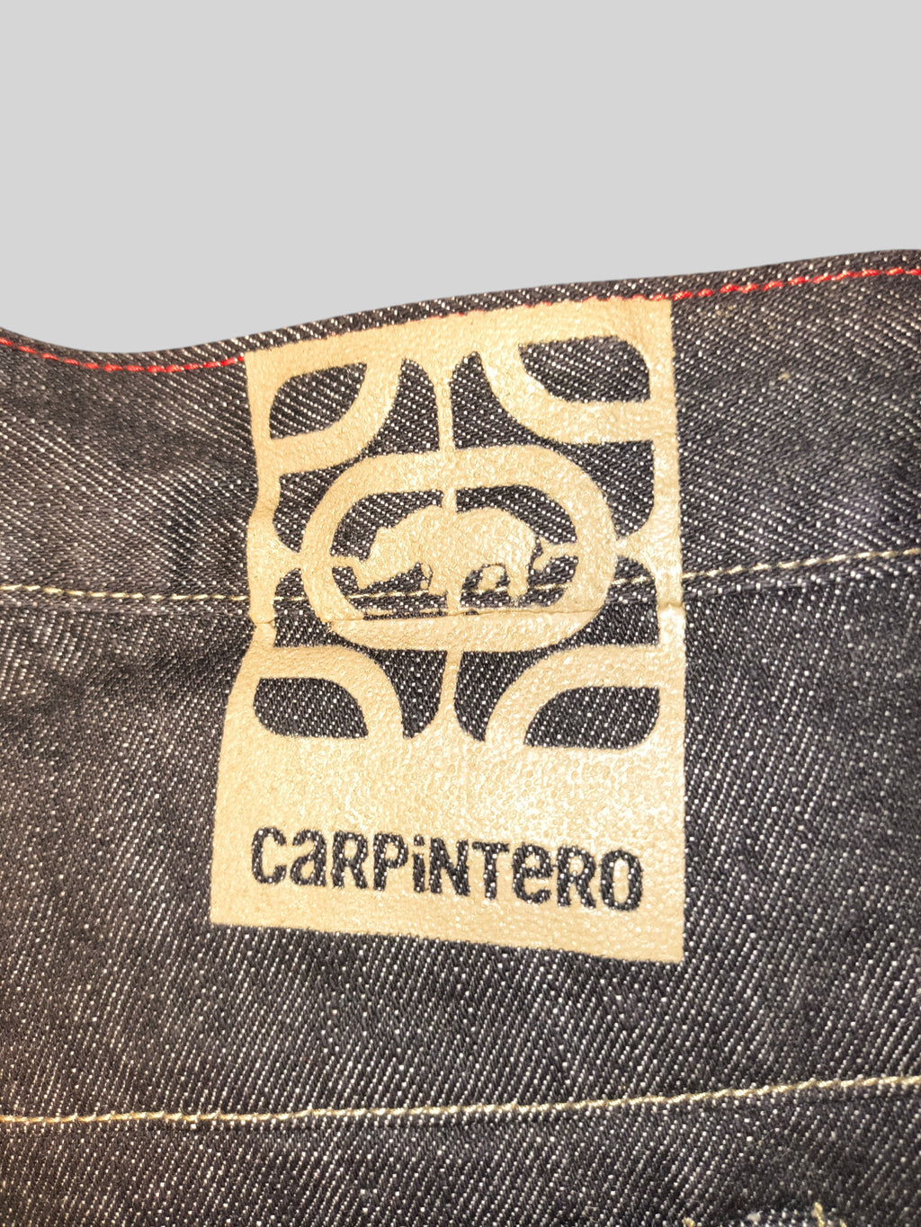 Awsum Thrift Ecko Carpintero dark denim jeans featuring a tan leather logo patch with contrast red stitching
