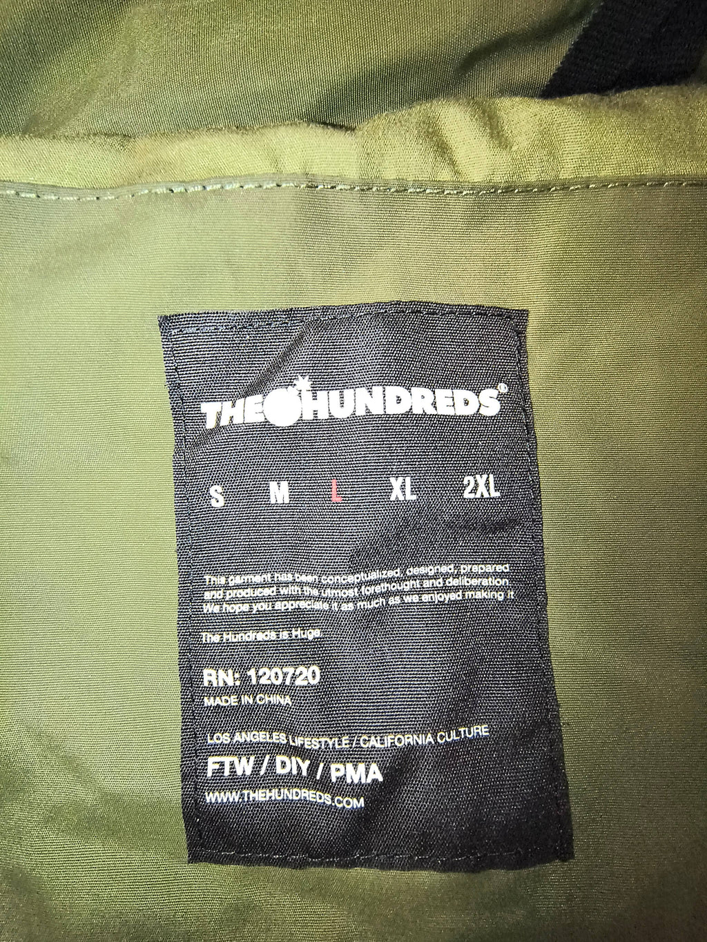 Awsum Thrift The Hundreds black fabric size tag for a men's large jacket with brand logo and care details